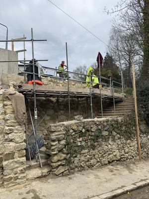 Stone wall repair scaffolding with workers in hi-vis