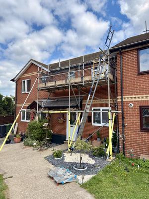 Red brick house scaffolding for chimney and roof repairs