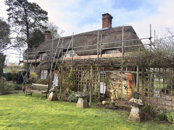 Thatched cottage with full scaffolding wrap